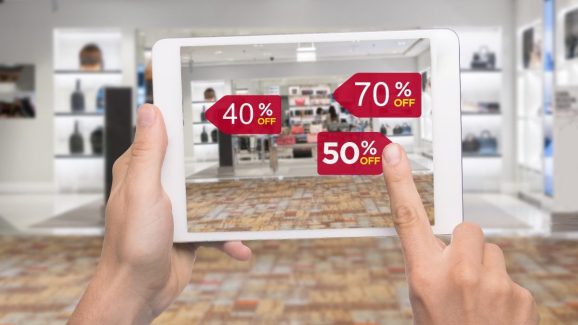 Augmented reality marketing concept. Hand holding digital tablet smart phone use AR application to check special sale price in retail fashion shop mall