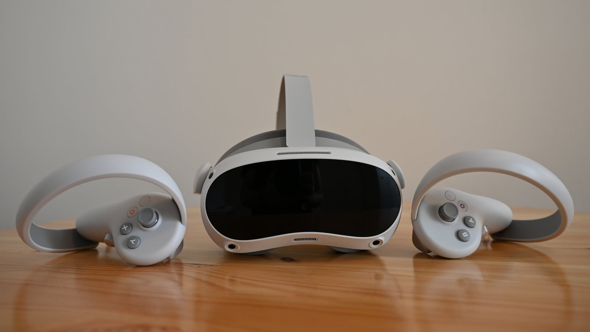 VR-Brille Pico 4 auf einem Tisch, von vorn, fankiert von den VR-Controllern
