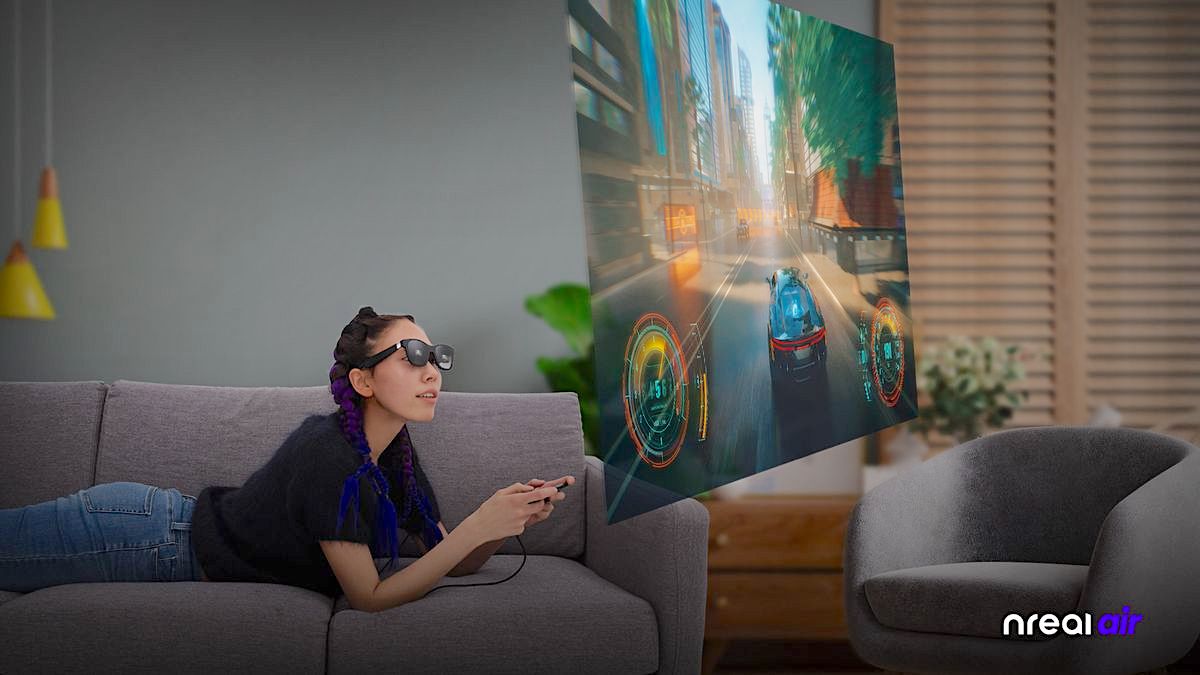 Eine Frau mit Neal Air auf der Nase liegt bäuchlings auf einem Sofa und spielt ein Videospiel auf einem virtuellen Monitor.